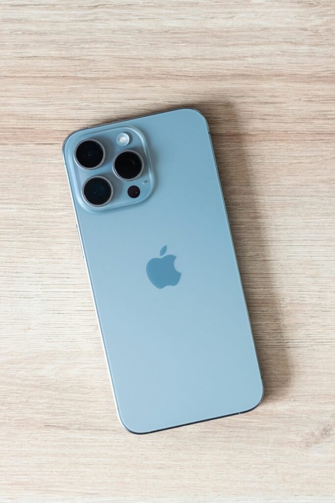 Close-up of a modern smartphone on a light wooden table surface.